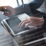 Man using mobile phone and working on laptop computer at home office. Casual business man freelancer online working, surfing the internet on smartphone, portable computer devices